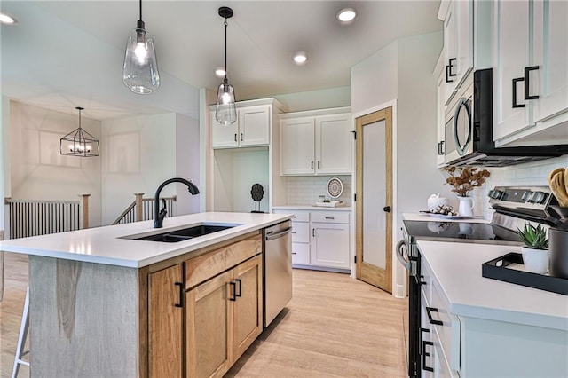 kitchen with stainless steel appliances, white cabinets, a center island with sink, and sink