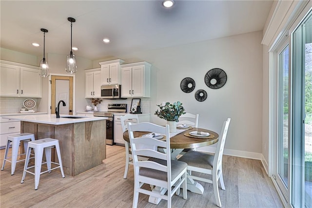 kitchen with stainless steel appliances, white cabinetry, a center island with sink, and a healthy amount of sunlight