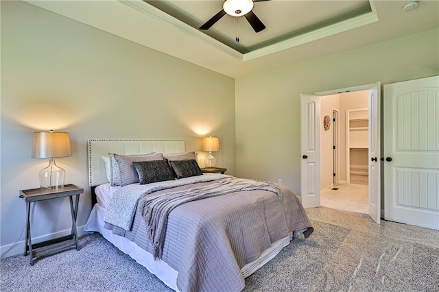 carpeted bedroom with ceiling fan, a tray ceiling, and a closet