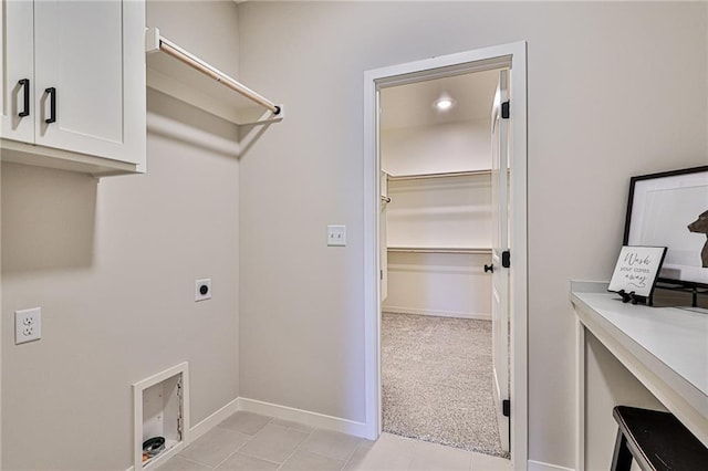 clothes washing area with light tile patterned flooring, hookup for an electric dryer, and cabinets