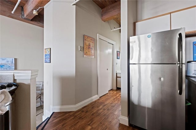 kitchen featuring stainless steel appliances, white cabinetry, wood finished floors, beamed ceiling, and baseboards