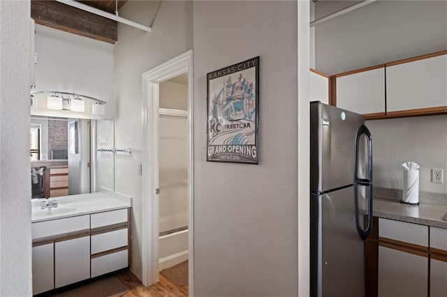 interior space featuring light wood finished floors, white cabinetry, a sink, and freestanding refrigerator