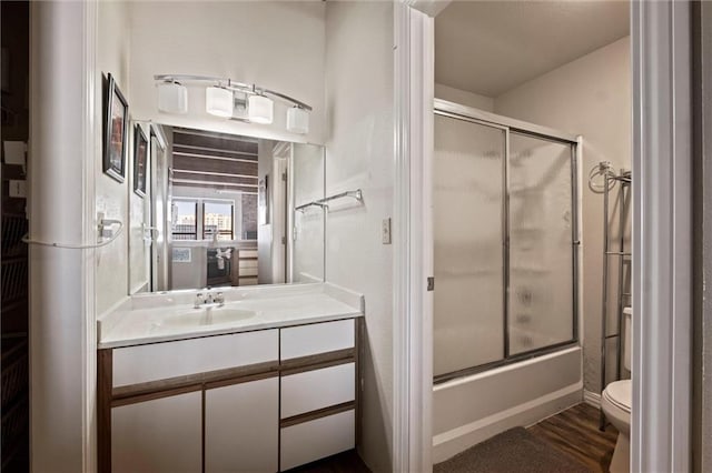 full bathroom with toilet, combined bath / shower with glass door, wood finished floors, and vanity