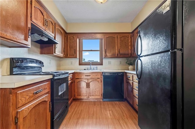 kitchen featuring a textured ceiling, light hardwood / wood-style flooring, sink, and black appliances