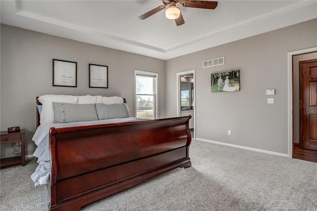 bedroom with light colored carpet, a tray ceiling, and ceiling fan