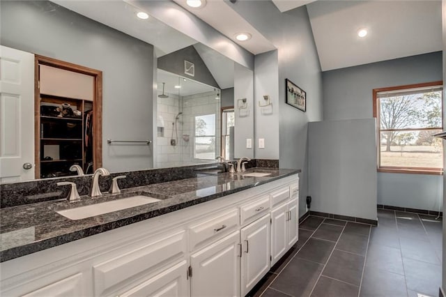 bathroom featuring vanity, a tile shower, vaulted ceiling, and tile patterned flooring