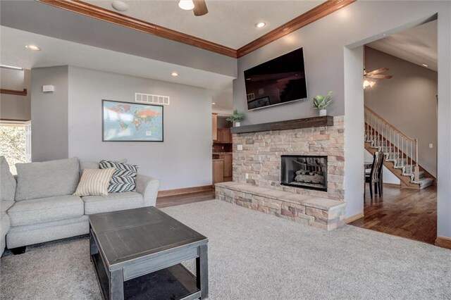 living room featuring ornamental molding, wood-type flooring, a fireplace, and ceiling fan