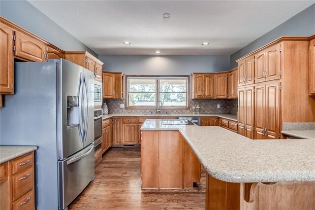 kitchen featuring sink, decorative backsplash, stainless steel appliances, and hardwood / wood-style flooring