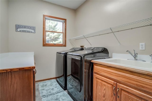 washroom with sink, washing machine and dryer, and cabinets