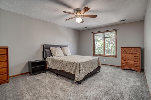 bedroom featuring a textured ceiling, light colored carpet, and ceiling fan