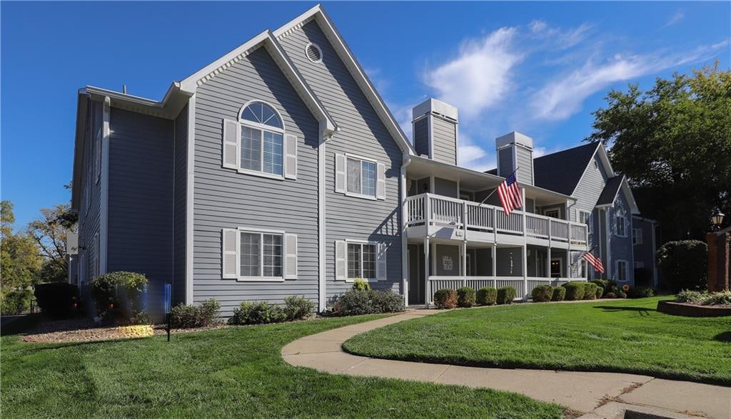 back of house featuring a lawn and a balcony