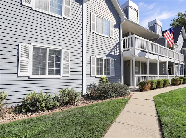 view of side of home featuring a yard and a balcony