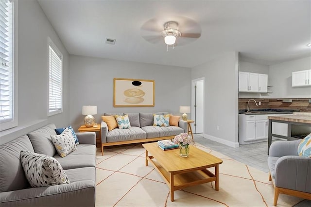 tiled living room featuring ceiling fan and sink