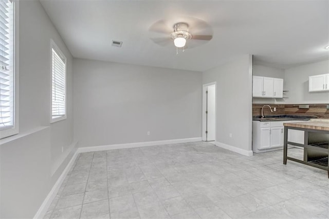 kitchen with ceiling fan, sink, tasteful backsplash, butcher block countertops, and white cabinetry