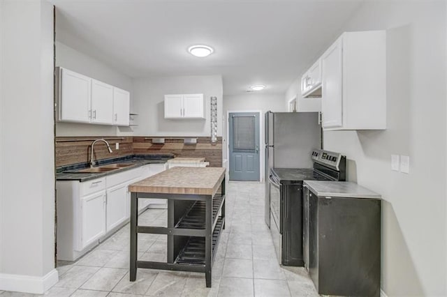 kitchen featuring stainless steel range with electric cooktop, white cabinets, sink, and tasteful backsplash