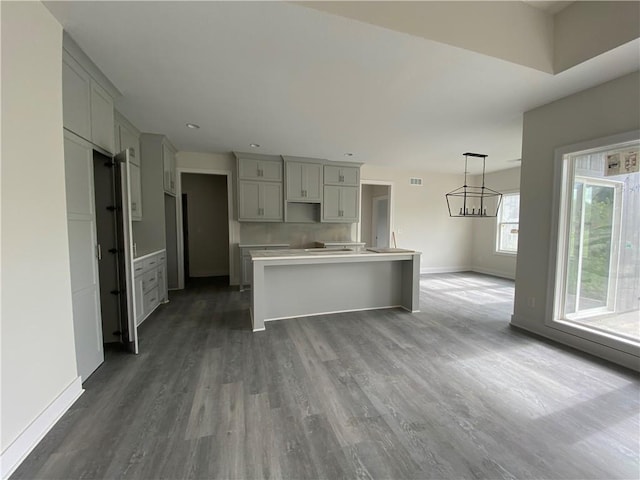 kitchen featuring a kitchen island, dark hardwood / wood-style floors, gray cabinetry, pendant lighting, and a chandelier