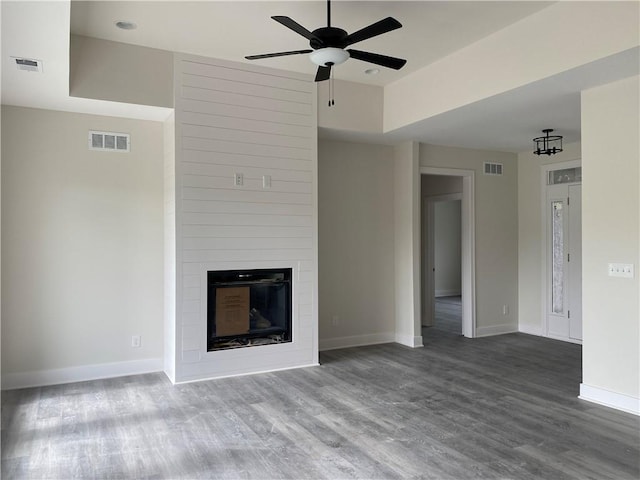 unfurnished living room with a large fireplace, hardwood / wood-style floors, and ceiling fan