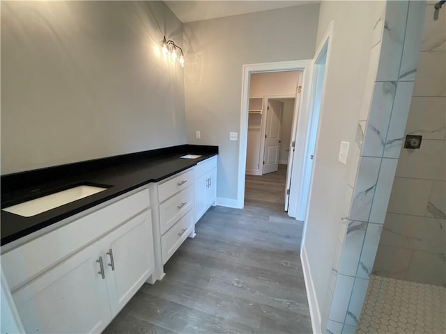 bathroom featuring wood-type flooring, vanity, and tiled shower