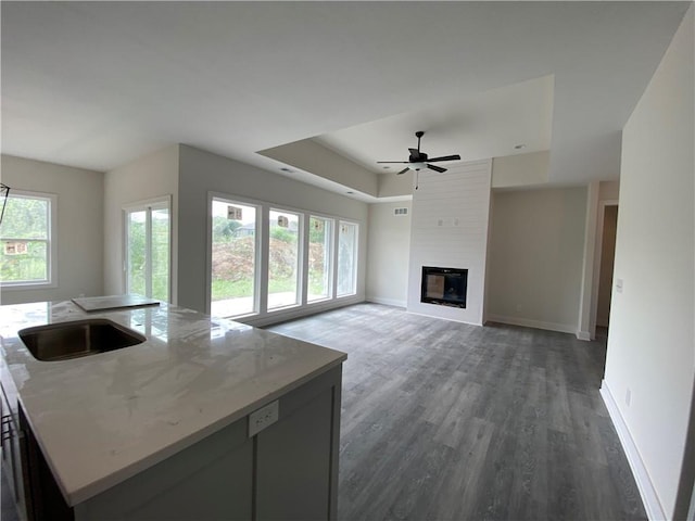 unfurnished living room with a fireplace, dark hardwood / wood-style floors, sink, and a wealth of natural light