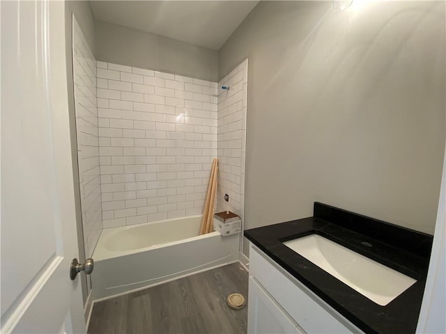 bathroom featuring wood-type flooring, tiled shower / bath, and vanity