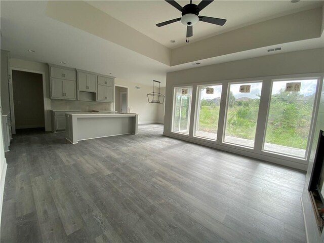 unfurnished living room with wood-type flooring and ceiling fan with notable chandelier