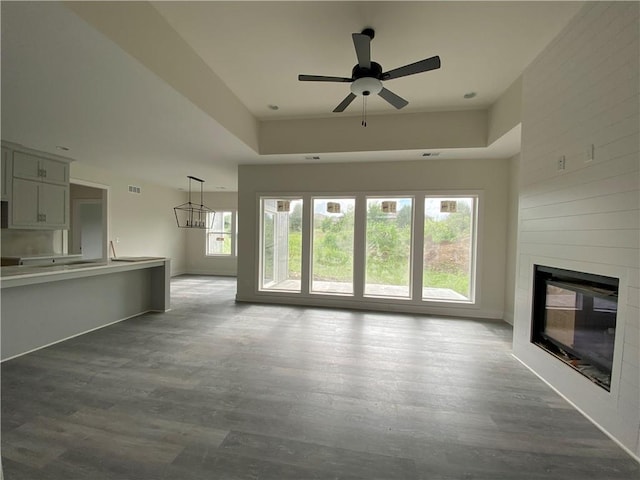 unfurnished living room with ceiling fan with notable chandelier, a fireplace, and hardwood / wood-style floors