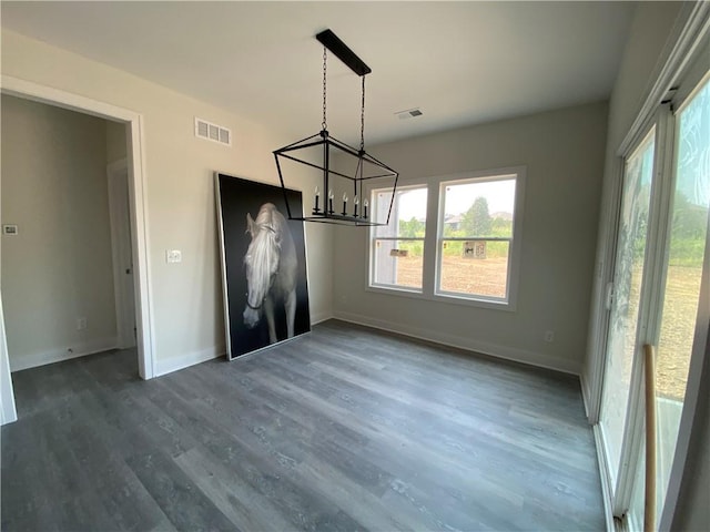 unfurnished dining area with a notable chandelier and dark wood-type flooring