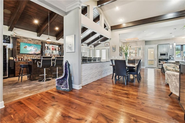 dining room with high vaulted ceiling, wood-type flooring, beamed ceiling, and indoor bar