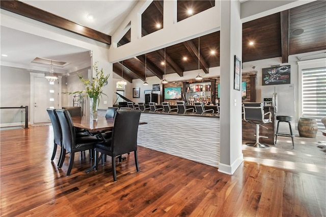 dining room with beam ceiling, hardwood / wood-style flooring, and high vaulted ceiling