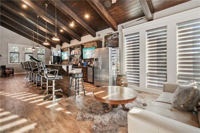 interior space featuring wood ceiling, vaulted ceiling with beams, stainless steel refrigerator with ice dispenser, hardwood / wood-style floors, and decorative light fixtures