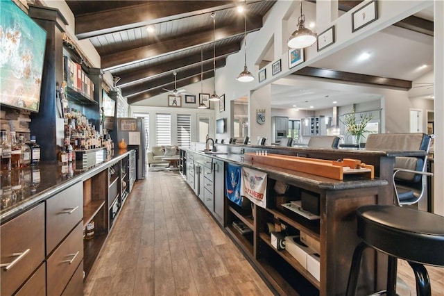 bar with vaulted ceiling with beams, dark brown cabinets, sink, hardwood / wood-style floors, and pendant lighting