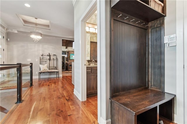 mudroom featuring sink, crown molding, light hardwood / wood-style flooring, and an inviting chandelier