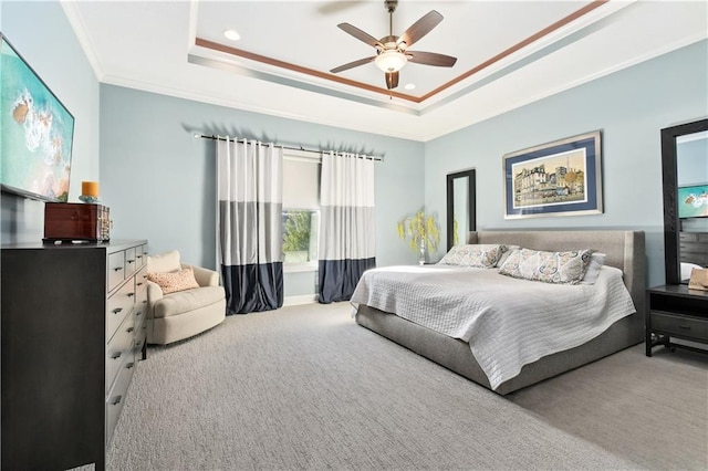 carpeted bedroom featuring ceiling fan, ornamental molding, and a tray ceiling