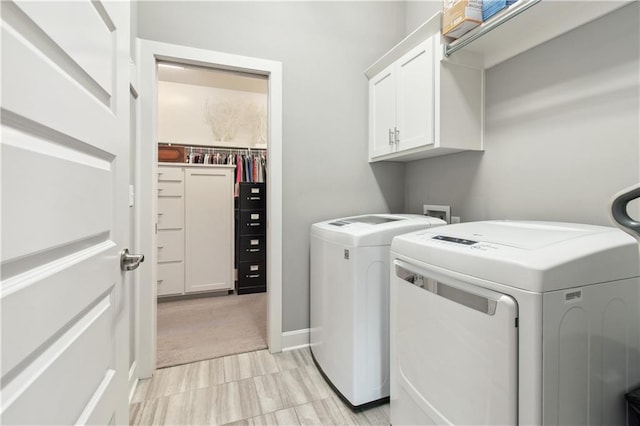 clothes washing area with washing machine and dryer and cabinets