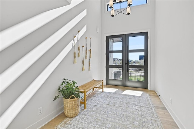 entryway with french doors, light hardwood / wood-style floors, and a notable chandelier