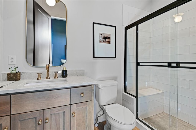 bathroom with hardwood / wood-style flooring, vanity, a shower with shower door, and toilet