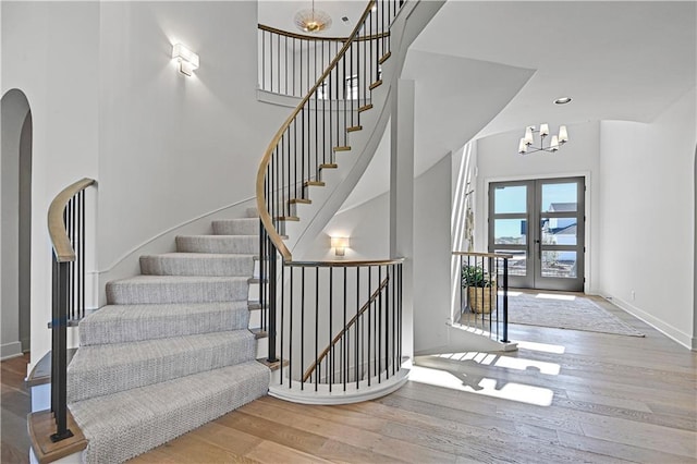 foyer featuring french doors, hardwood / wood-style floors, a high ceiling, and a notable chandelier