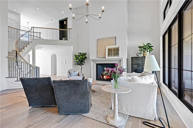 living room featuring a chandelier, light hardwood / wood-style floors, and a high ceiling