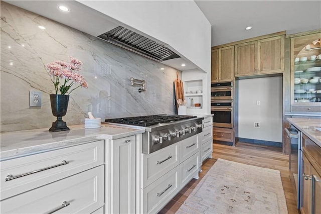 kitchen featuring decorative backsplash, light stone counters, stainless steel appliances, light hardwood / wood-style flooring, and white cabinets