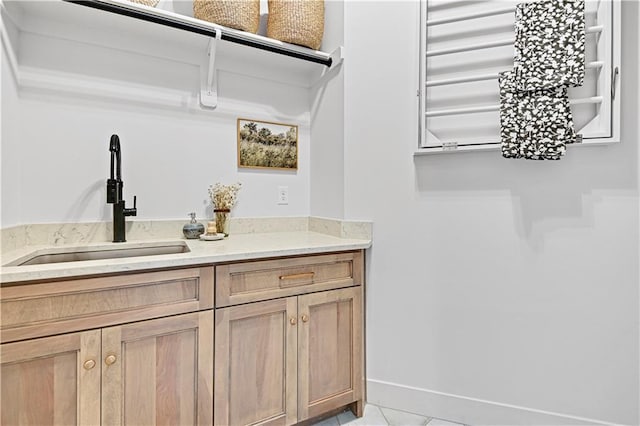 bar featuring light tile patterned flooring, sink, and light brown cabinets