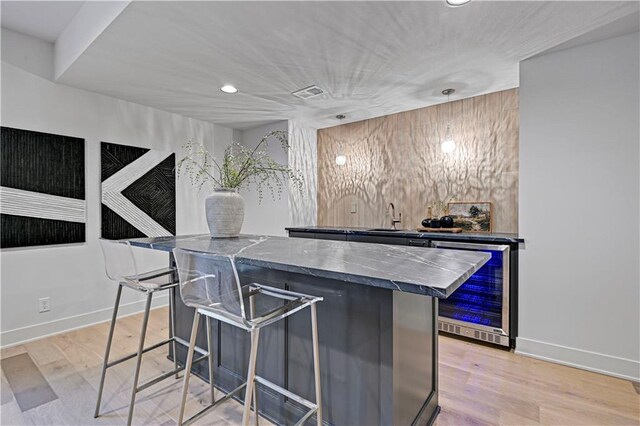 bar featuring wine cooler, light hardwood / wood-style flooring, and sink