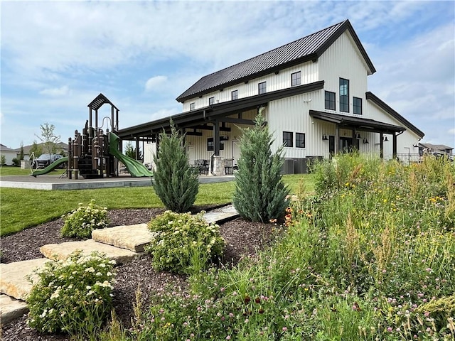 rear view of property featuring a playground and a lawn