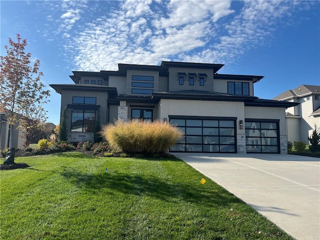 prairie-style home with stucco siding, stone siding, concrete driveway, a front yard, and a garage