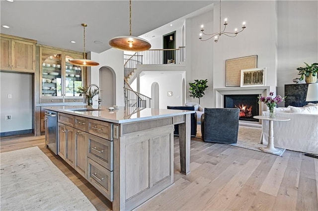 17004 Parkhill St, Overland Park, KS 66221 - kitchen featuring a sink, stainless steel dishwasher, arched walkways, light wood-style flooring, and a towering ceiling