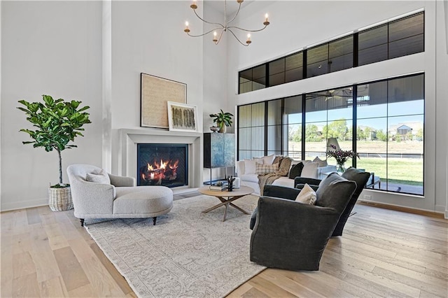 17004 Parkhill St, Overland Park, KS 66221 - living room with baseboards, wood finished floors, a lit fireplace, a chandelier, and a high ceiling