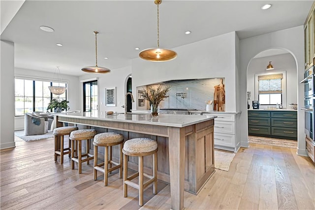 17004 Parkhill St, Overland Park, KS 66221 - kitchen featuring light wood finished floors, recessed lighting, a large island with sink, a kitchen breakfast bar, and a sink
