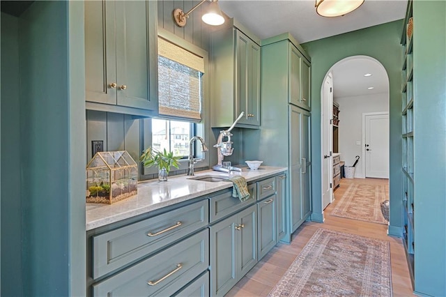 17004 Parkhill St, Overland Park, KS 66221 - kitchen with arched walkways, light wood finished floors, green cabinets, light stone counters, and a sink