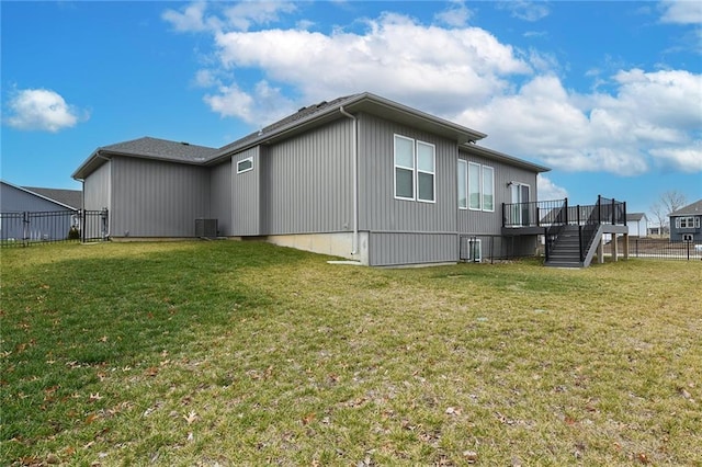 rear view of property with a lawn, a wooden deck, and central AC