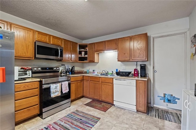 kitchen featuring a textured ceiling, stainless steel appliances, and sink