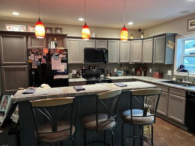 kitchen with a breakfast bar, decorative light fixtures, sink, decorative backsplash, and black appliances